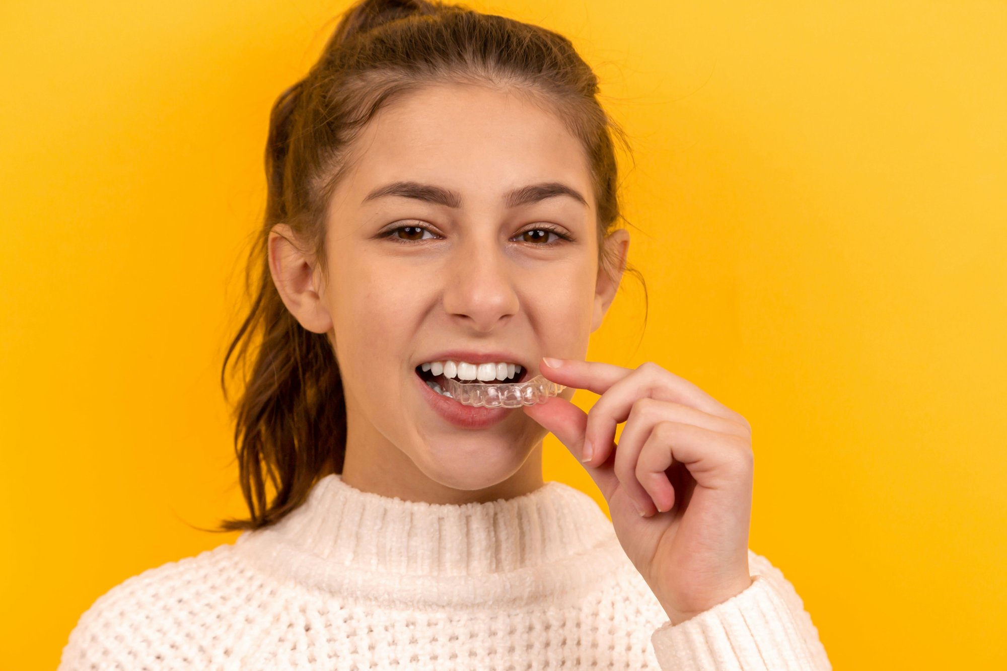Young woman inserting a clear aligner — Invisalign at Dr Pierre Dentistry Edgecliff